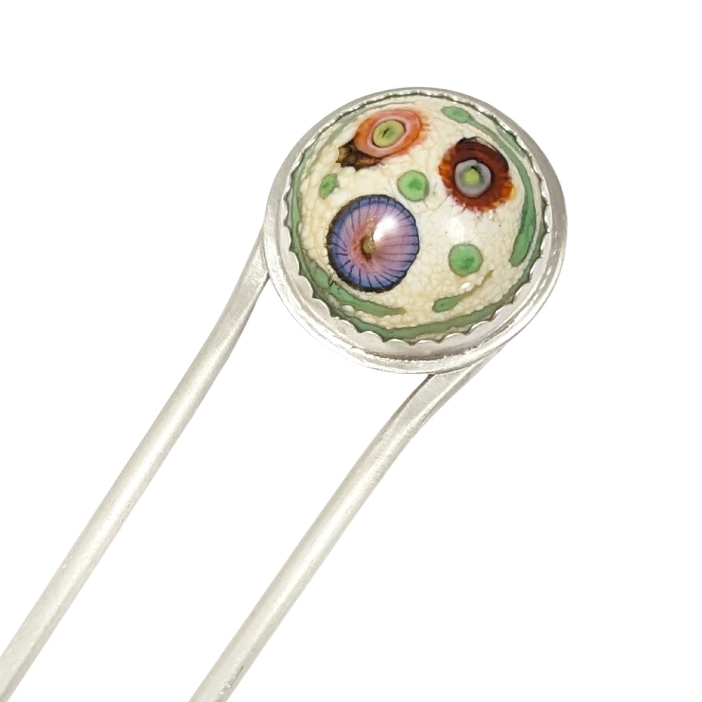 Sterling silver hair fork with a round lampwork glass stone at the top. The glass is pale yellow with ribbons of green around the edge and three abstract forms that look like flowers - one red, one orange, and one blue/pink.