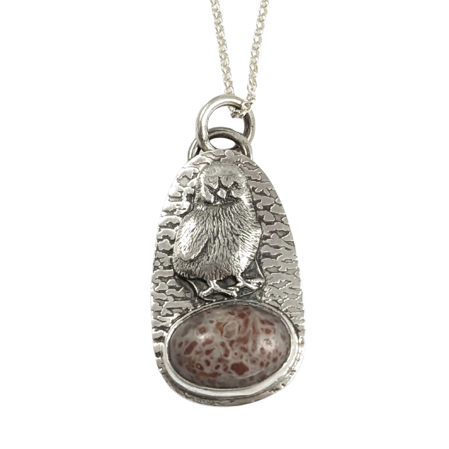 Egg shaped sterling silver pendant with a three dimensional baby chick above an oval speckled stone. The background is textured.