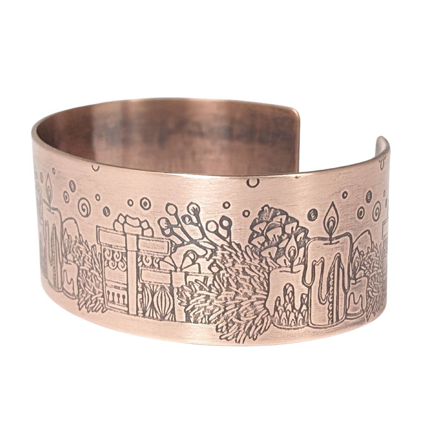 copper cuff bracelet with a christmas theme. the cuff is covered in impressions of candles, wrapped gifts, and evergreens