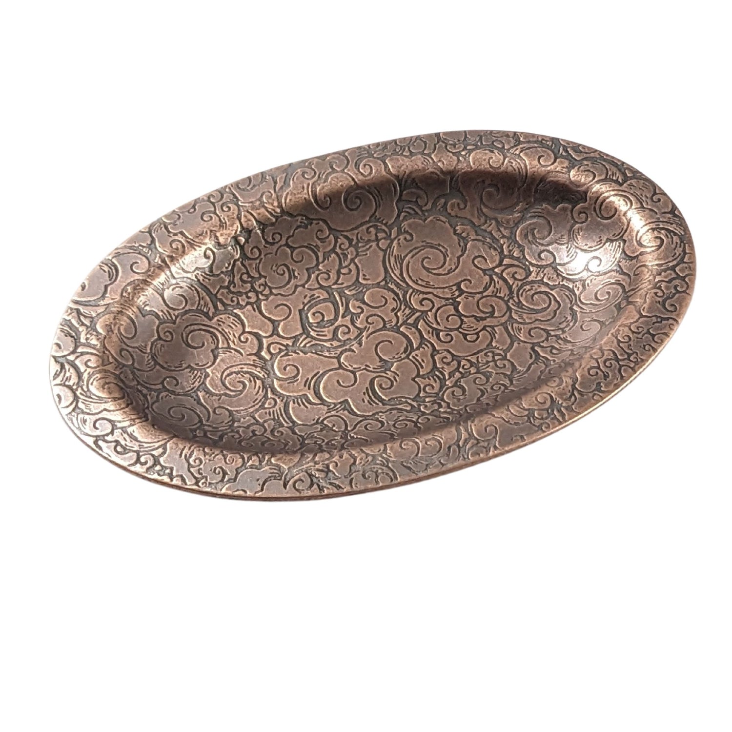 An oval copper ring dish with a raised edge. The dish has an impressed pattern of clouds.