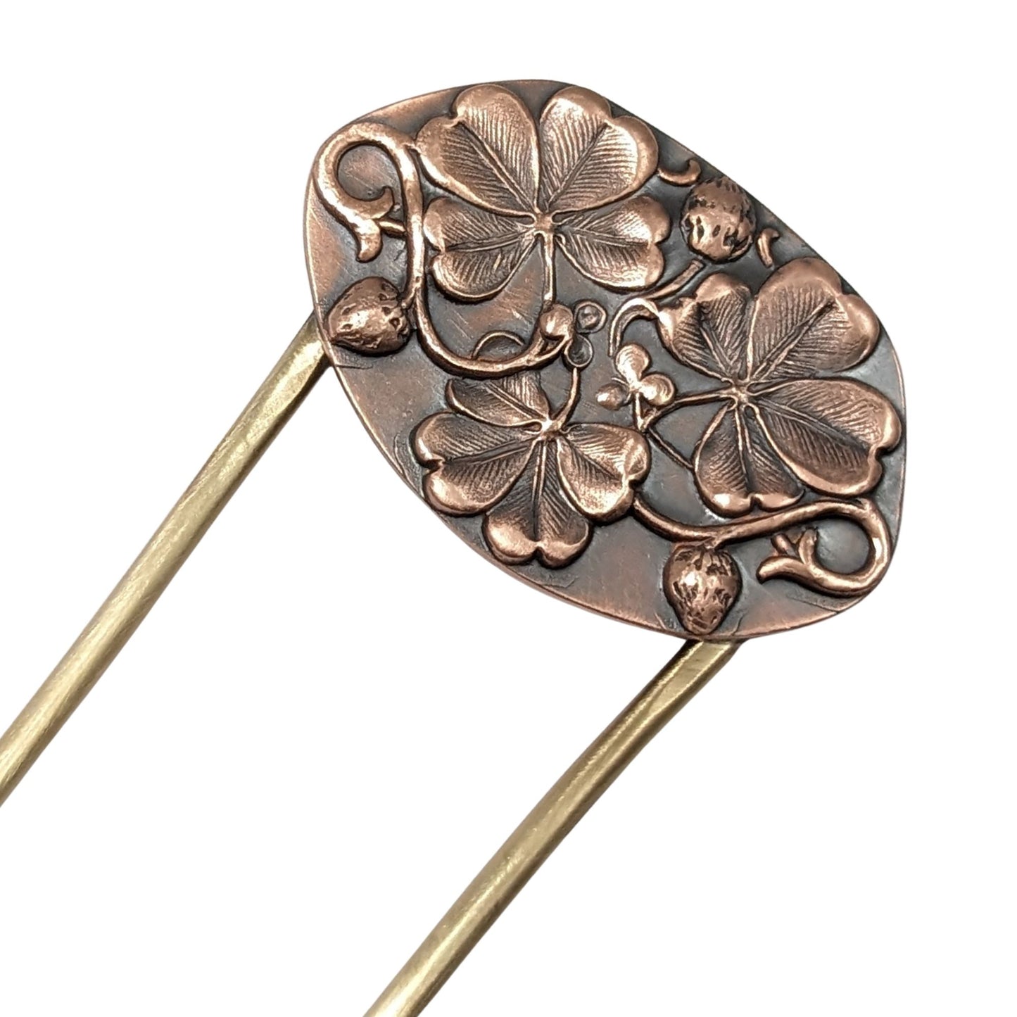 An oval copper hair fork with an emobsed design of three large four leaf clovers. Accented with vines and three small strawberries, the forks are brass.