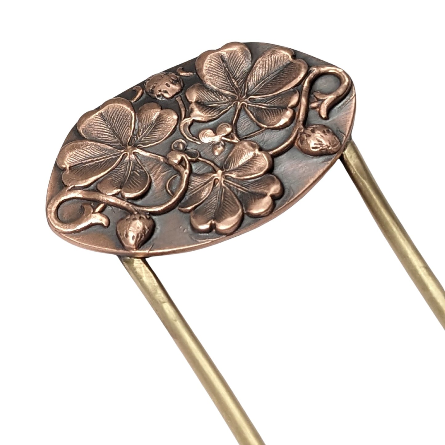 An oval copper hair fork with an emobsed design of three large four leaf clovers. Accented with vines and three small strawberries, the forks are brass.