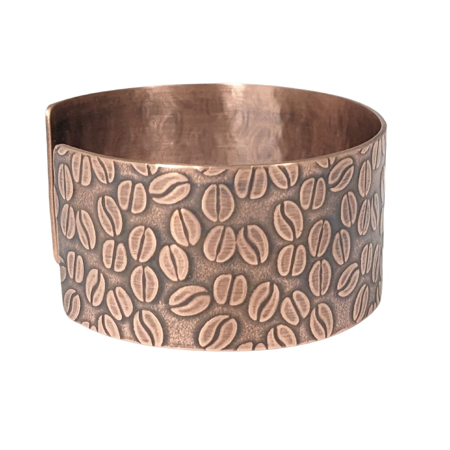 Copper cuff bracelet covered with impressed design of coffee beans.