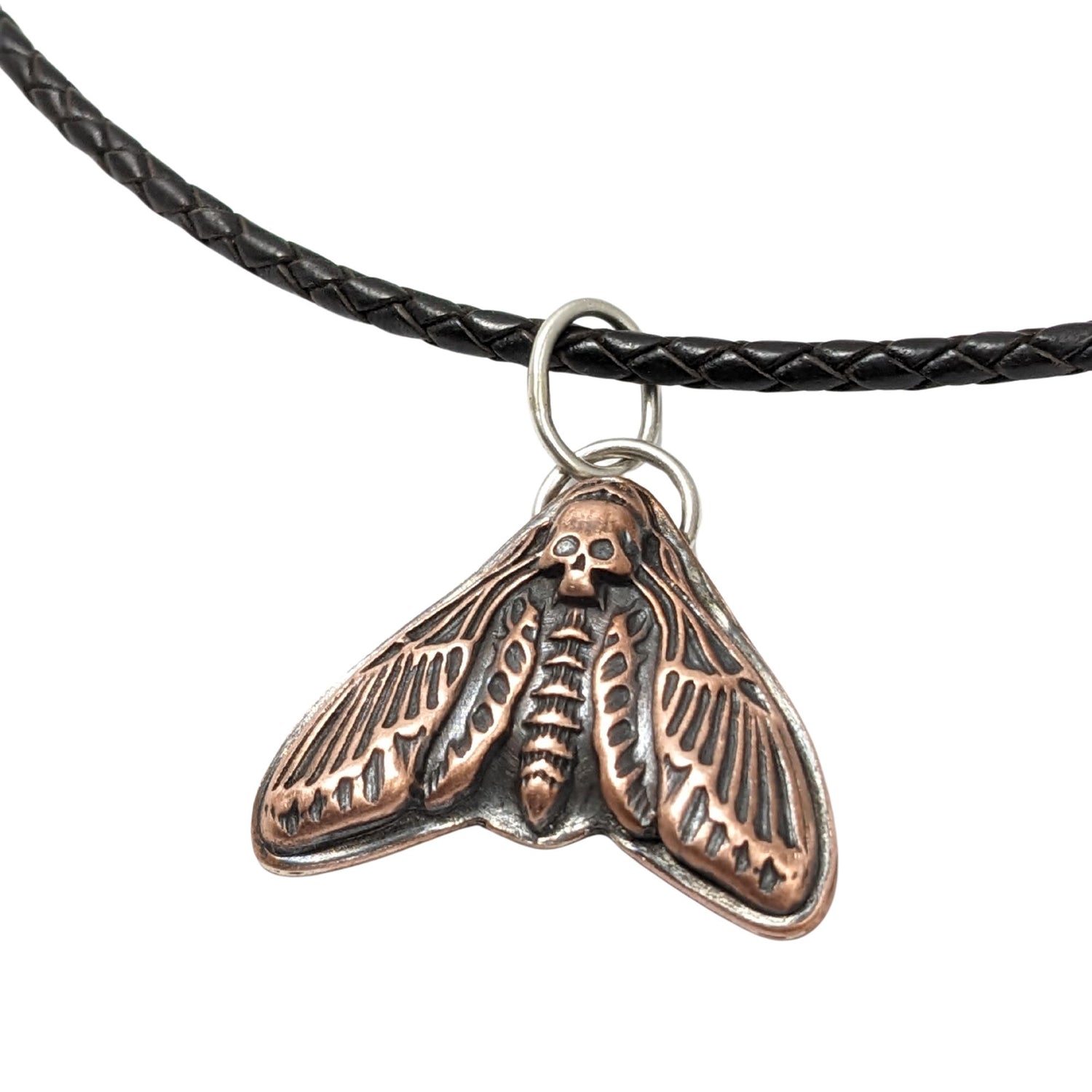 Large copper moth pendant on a leather cord. The moth is called a death's head, so the head on this piece is a skull design.