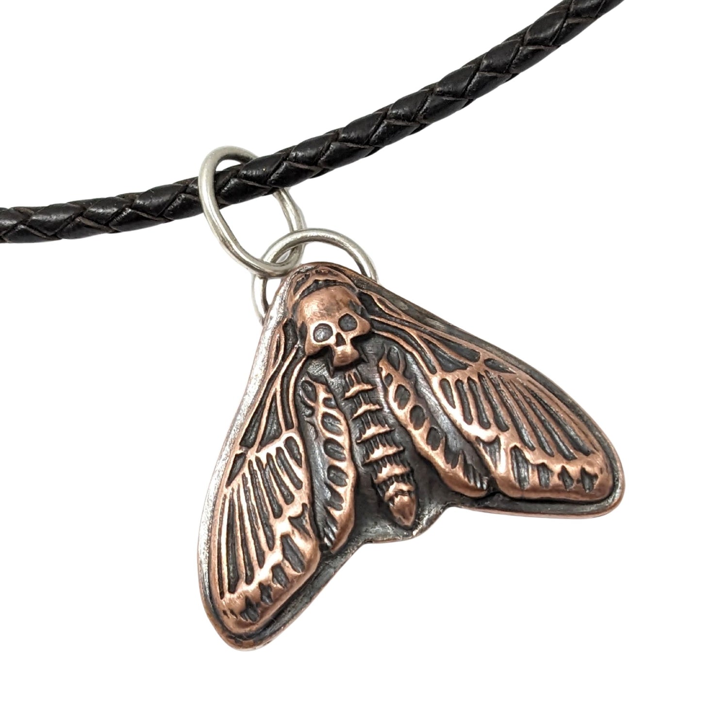 Large copper moth pendant on a leather cord. The moth is called a death's head, so the head on this piece is a skull design.
