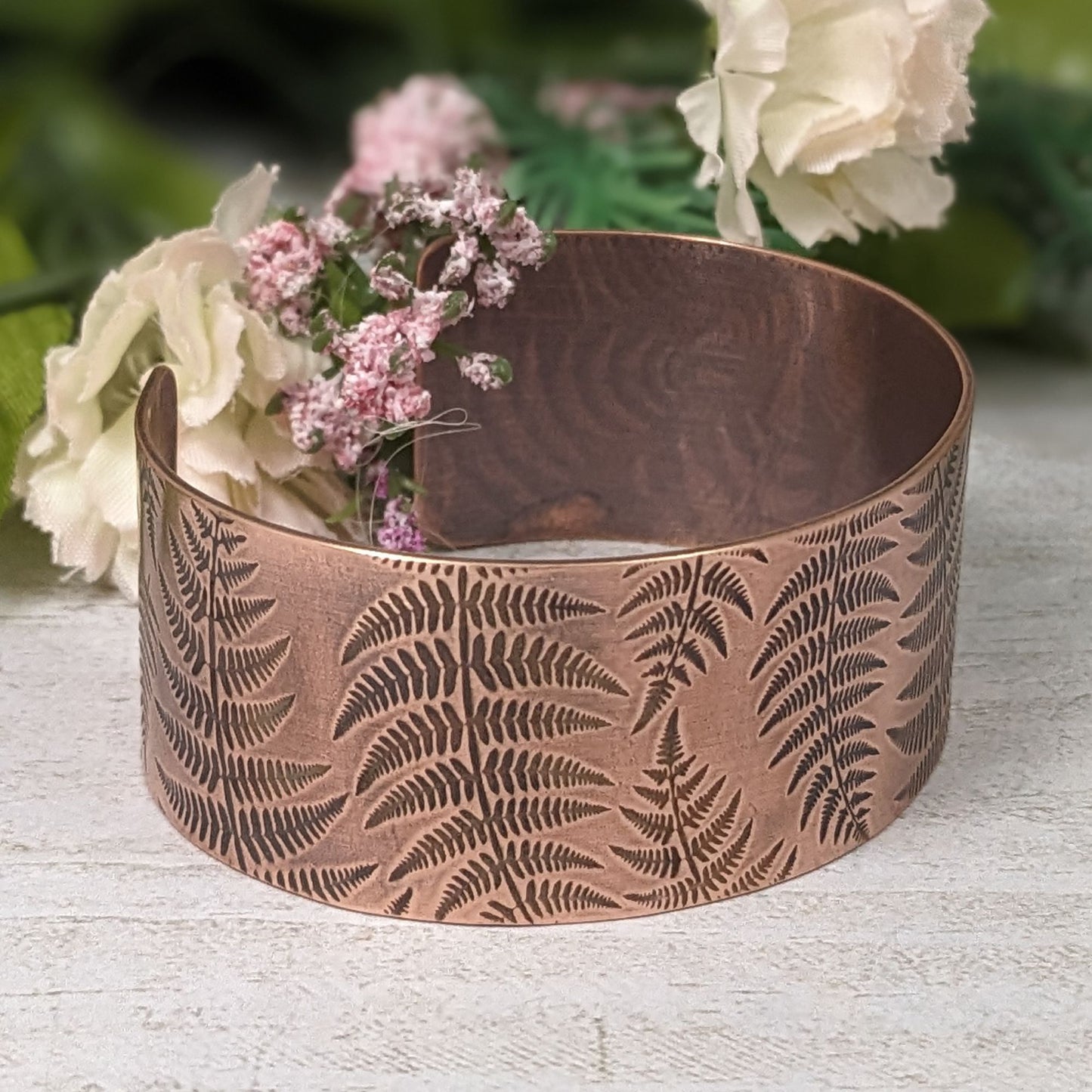 copper cuff bracelet covered in  impressions of fern fronds.
