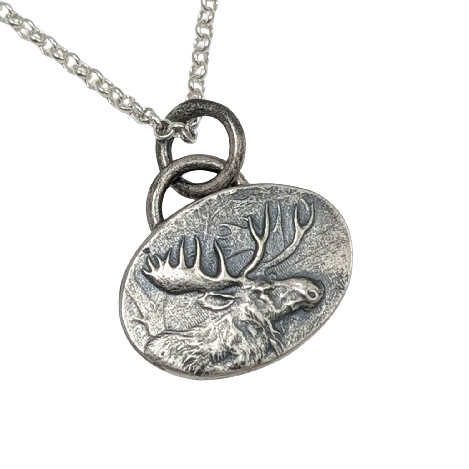Oval silver pendant with a raised design of a moose, most of the body and all of the head and antlers.