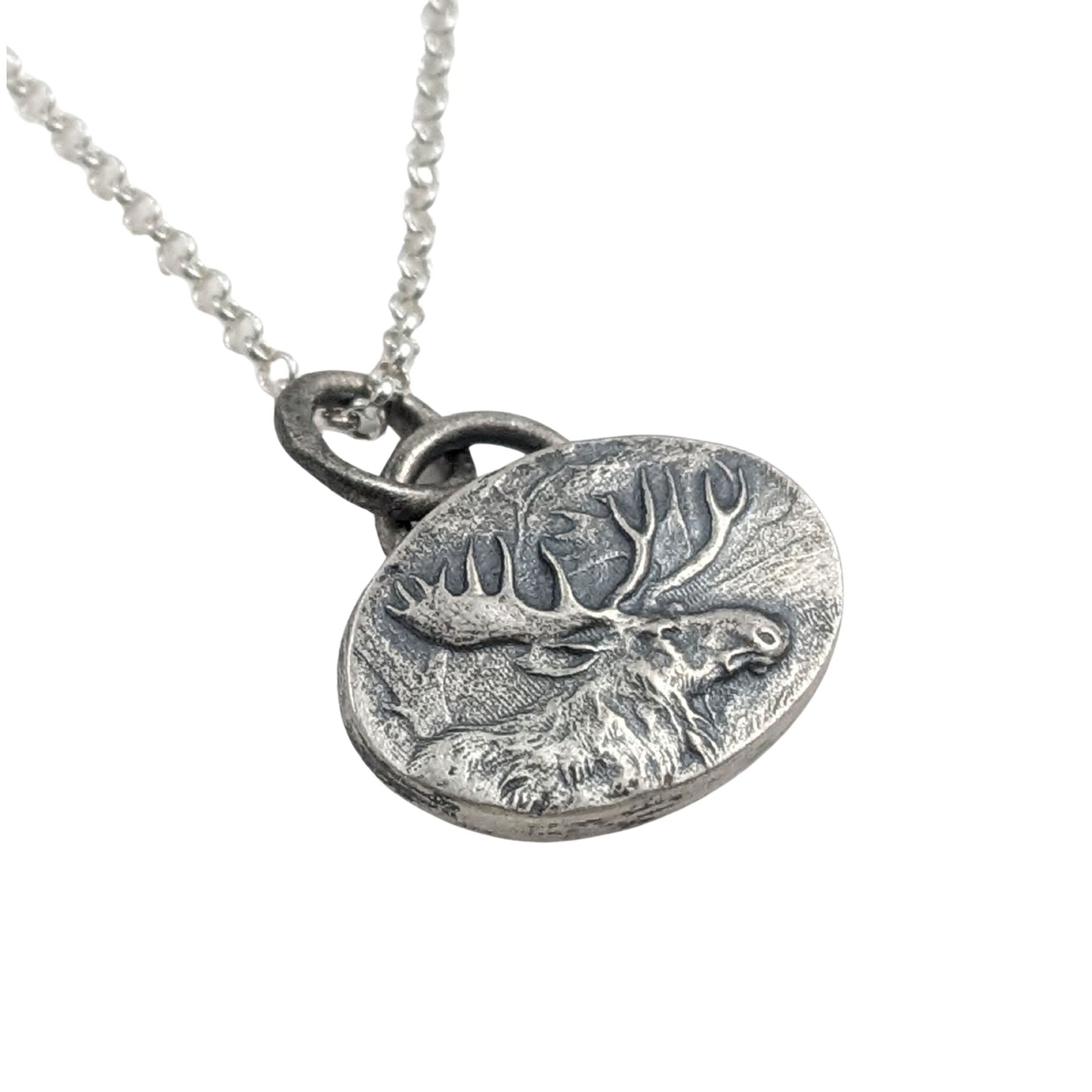 Oval silver pendant with a raised design of a moose, most of the body and all of the head and antlers.