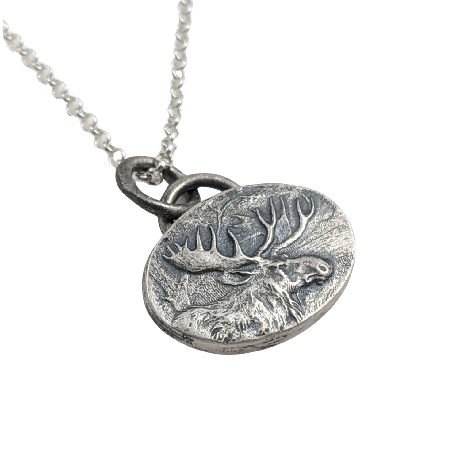 Oval silver pendant with a raised design of a moose, most of the body and all of the head and antlers.