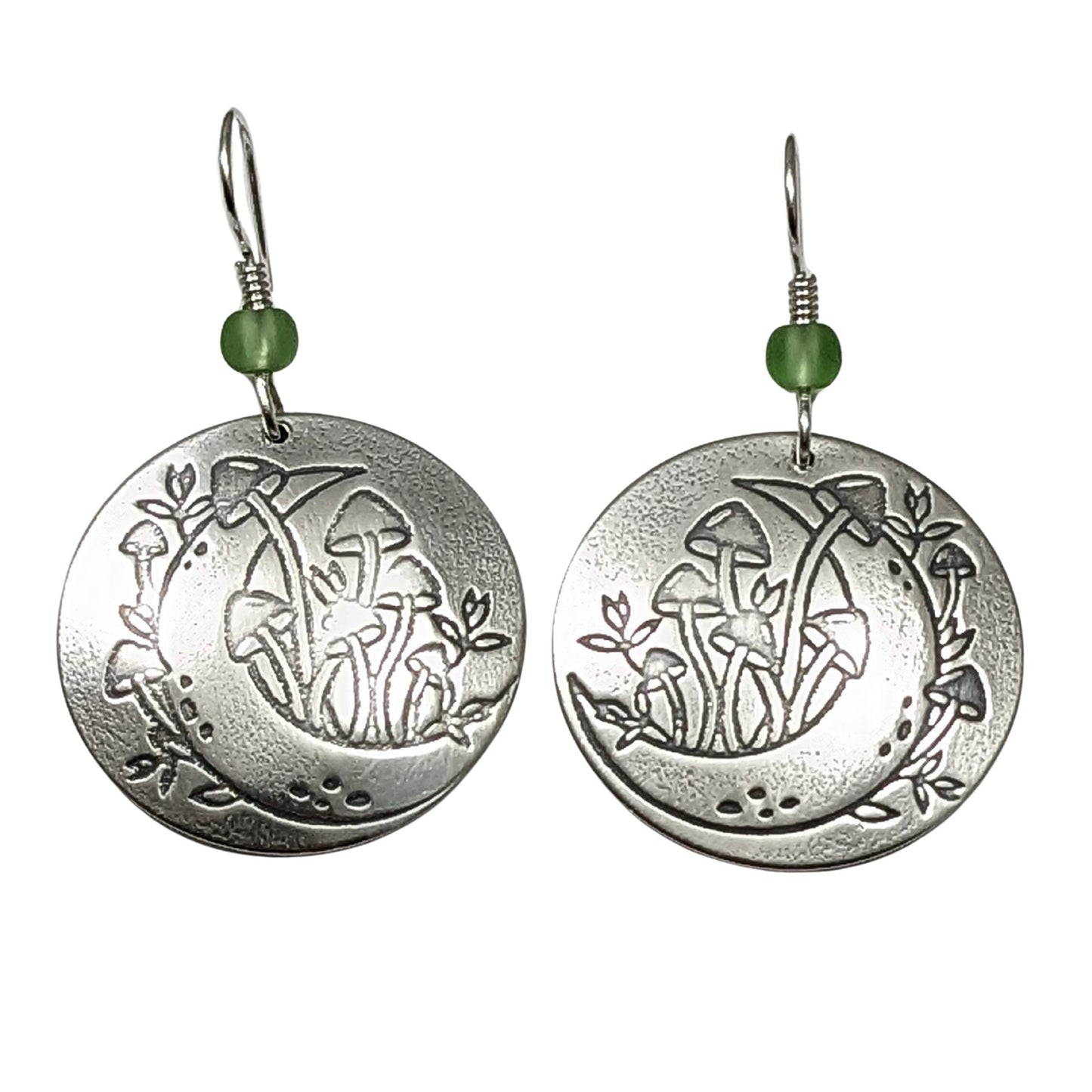 A pair of domed sterling silver round drop earrings featuring an engraved mushroom and crescent moon design, accented with small green beads and silver ear wires.