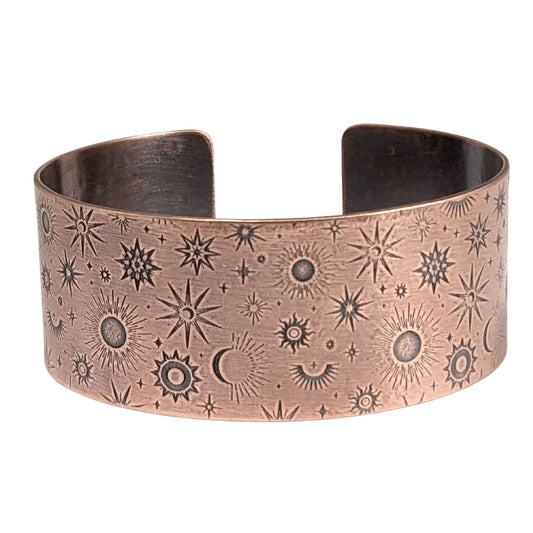 A one inch wide copper cuff bracelet covered in an impressed design of stars and planets.