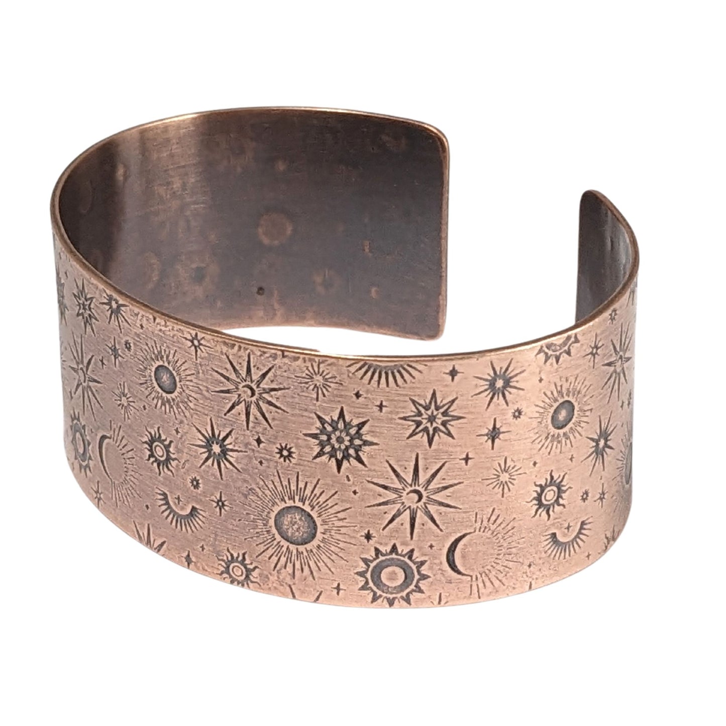 A one inch wide copper cuff bracelet covered in an impressed design of stars and planets.