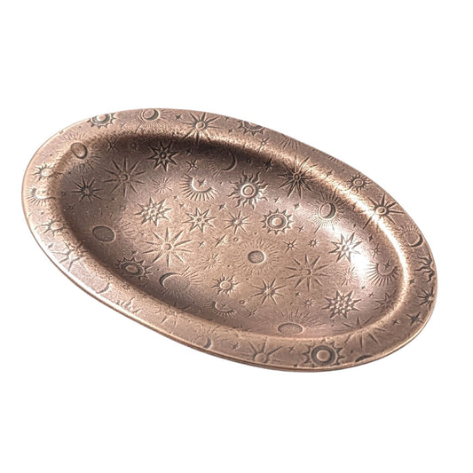 An oval copper ring dish with a raised edge. The dish has an impressed pattern of various star deisgns.
