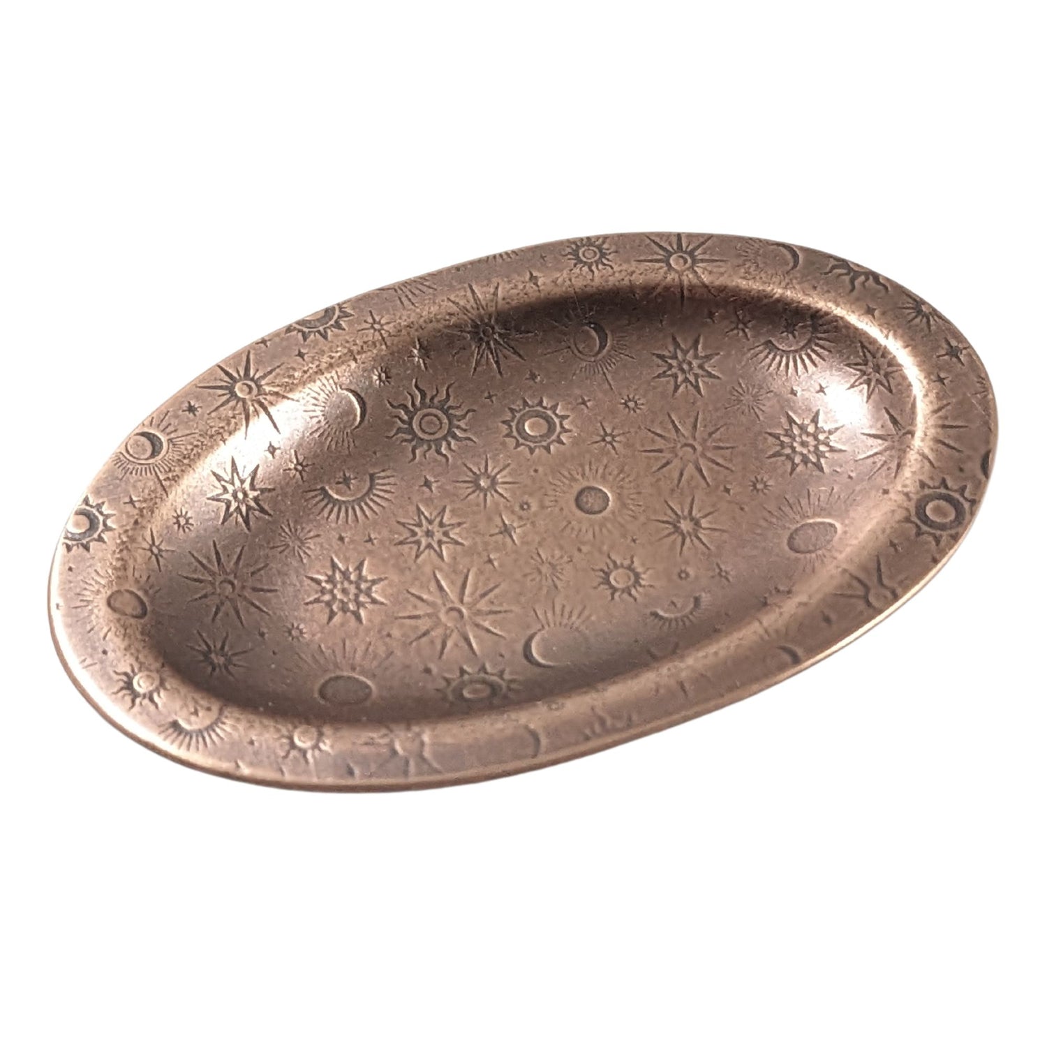 An oval copper ring dish with a raised edge. The dish has an impressed pattern of various star deisgns.