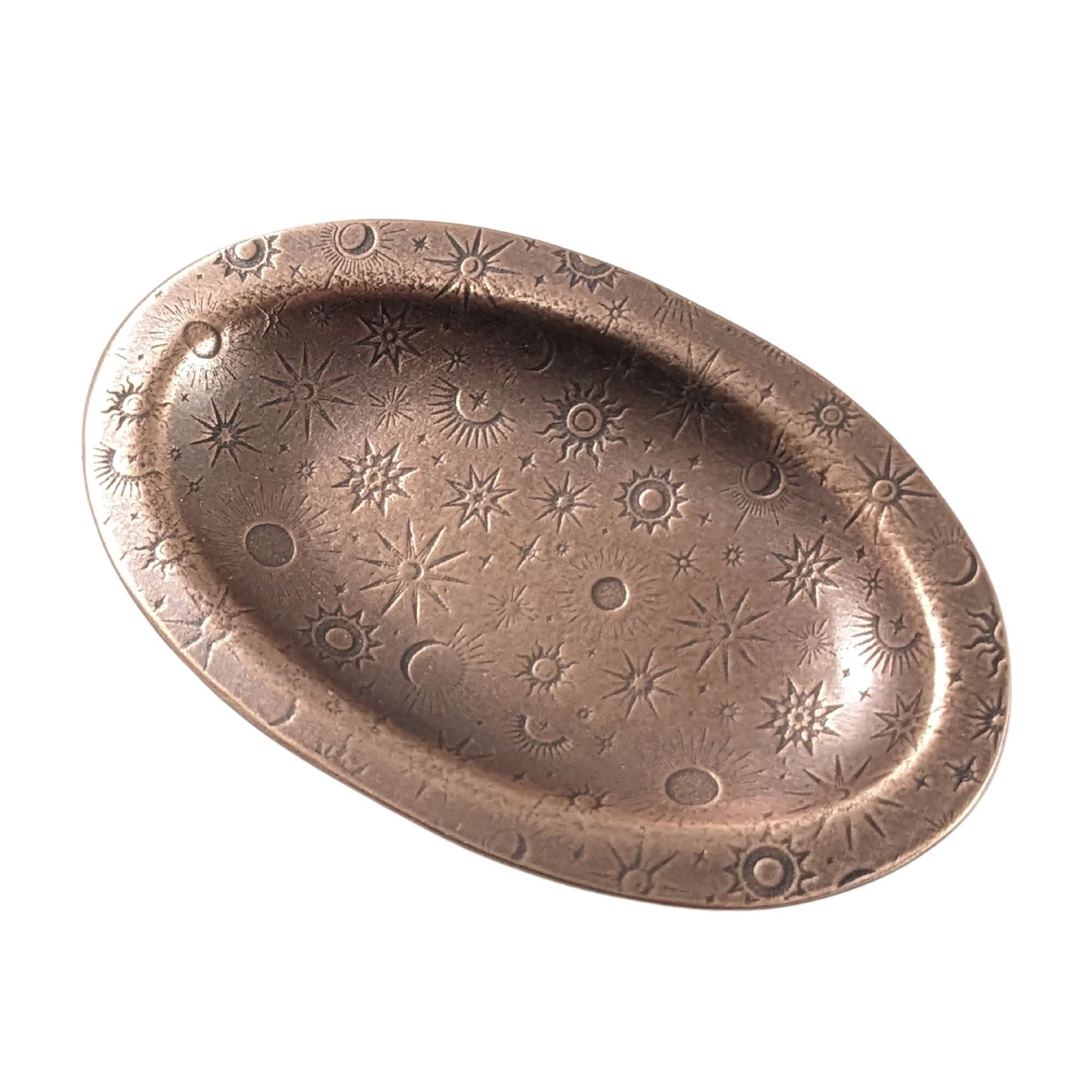 An oval copper ring dish with a raised edge. The dish has an impressed pattern of various star deisgns.