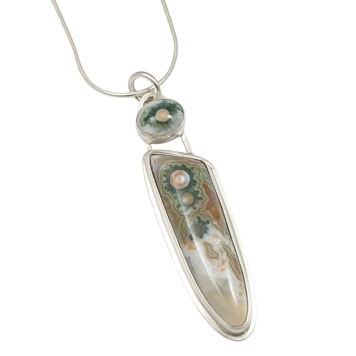 Long narrow sterling silver pendant. The main stone is clear toward the bottom, the rest is whit and orange background with three green cogwheel shaped designs with orange centers. A top accent stone has the same white, green, and orange combination.