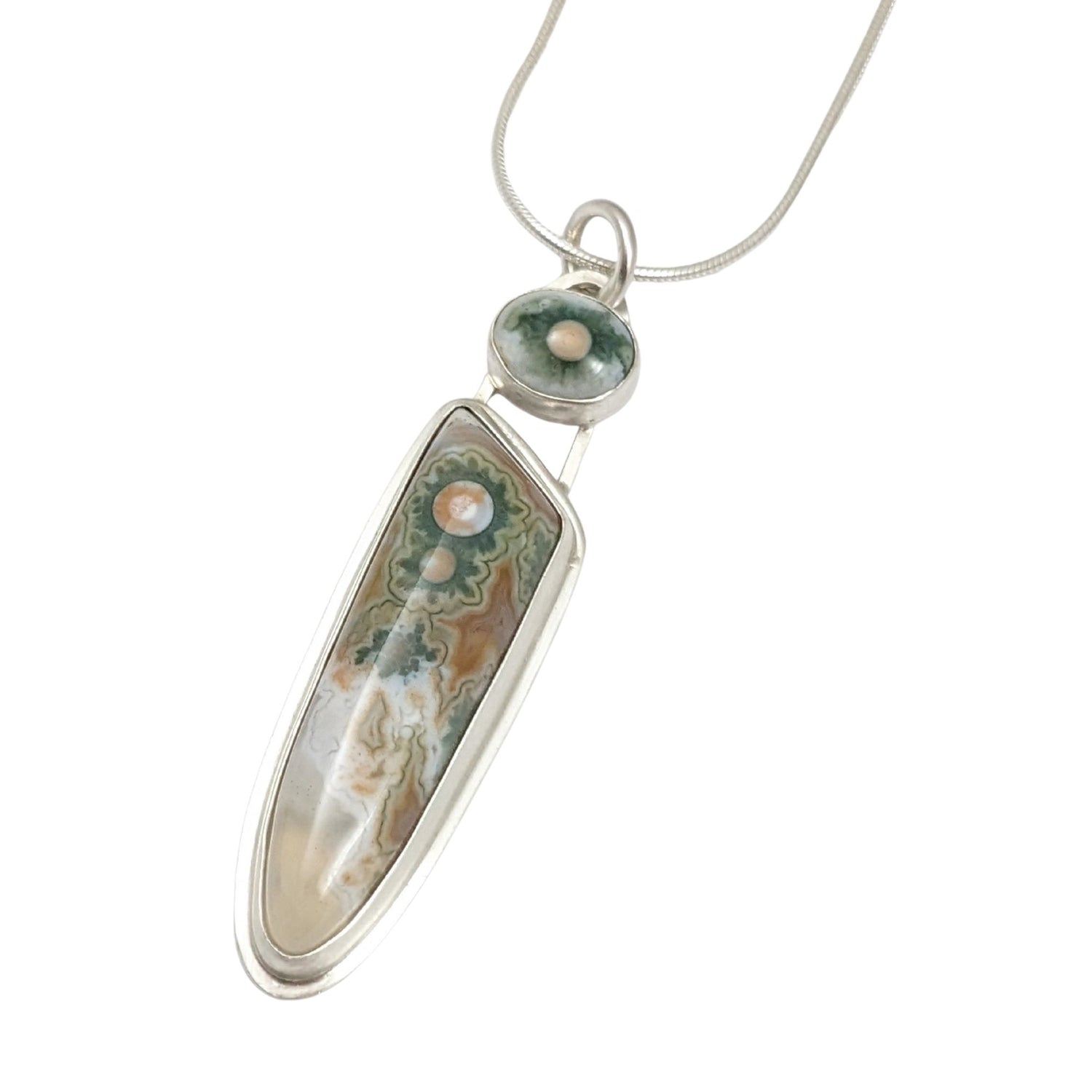 Long narrow sterling silver pendant. The main stone is clear toward the bottom, the rest is whit and orange background with three green cogwheel shaped designs with orange centers. A top accent stone has the same white, green, and orange combination.
