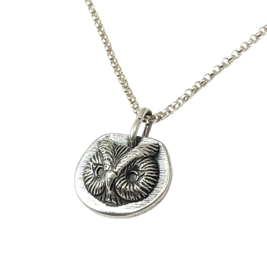 Sterling silver pendant of an owl face. The pendant is three dimensional and thick.