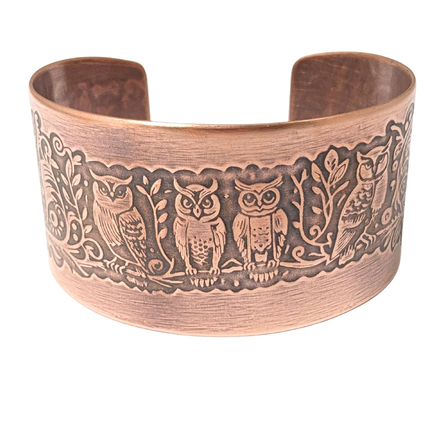 Wide tapered copper cuff bracelet. A design of various owls on a tree branch wraps the entire length of the bracelet.