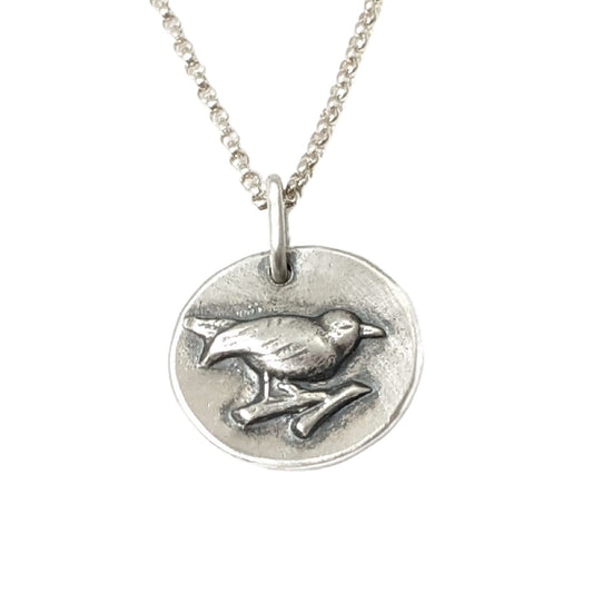 Small round sterling silver pendant with a songbird perched on a branch.