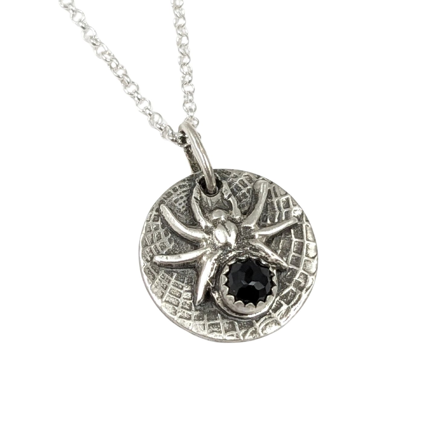 Round sterling silver pendant with a detailed black widow spider on a web texture background. The spider's body is a rose cut black onyx gemstone.