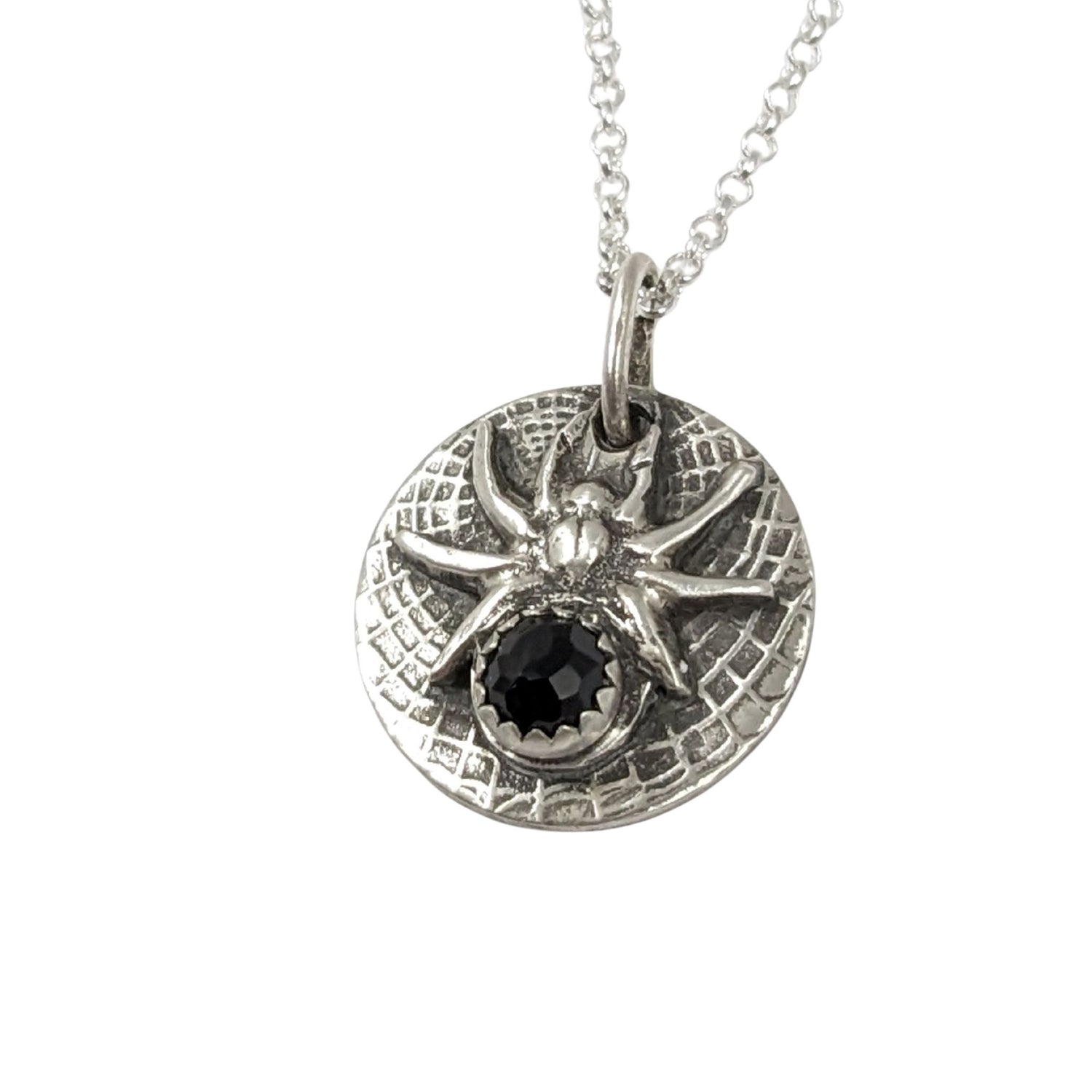 Round sterling silver pendant with a detailed black widow spider on a web texture background. The spider's body is a rose cut black onyx gemstone.