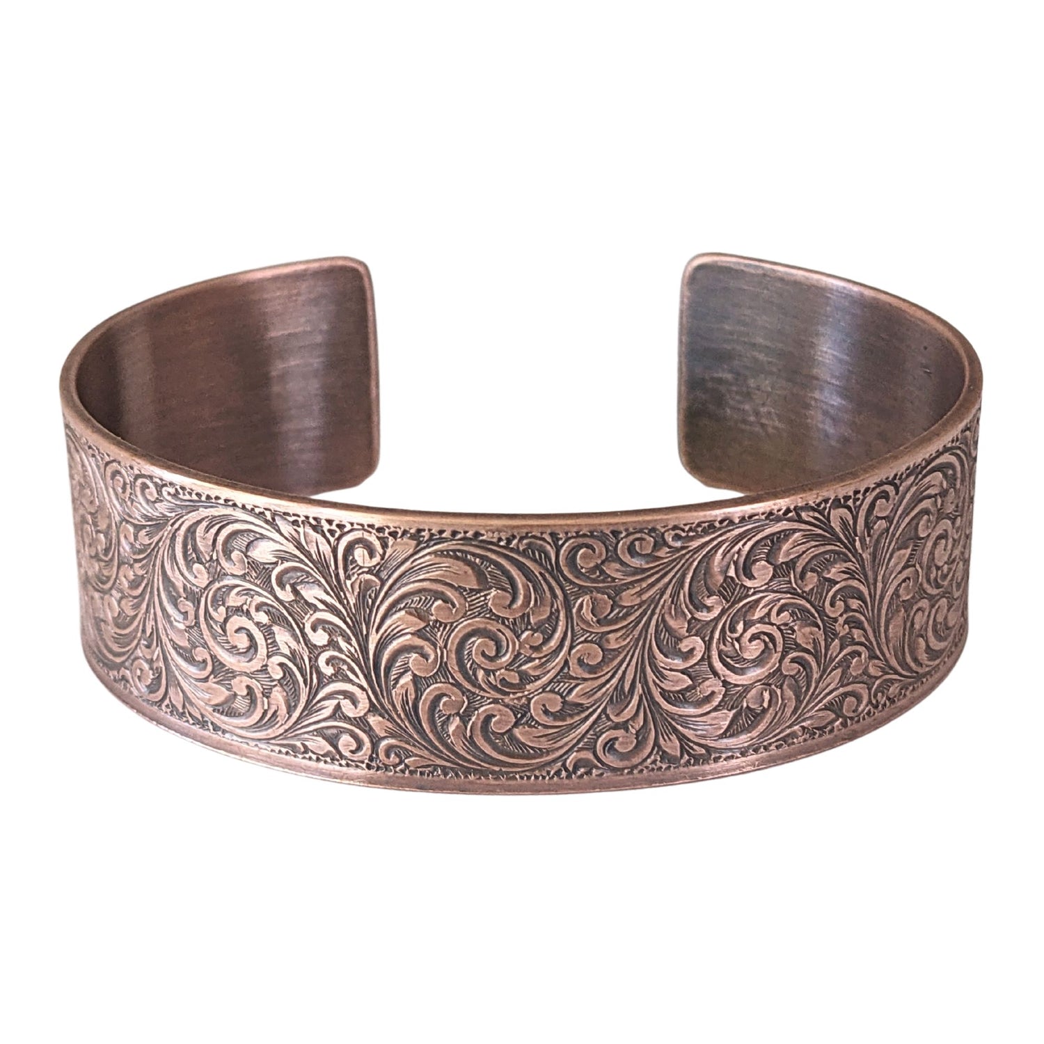 copper cuff bracelet with a detailed design of flourishes in a repeated spiral pattern