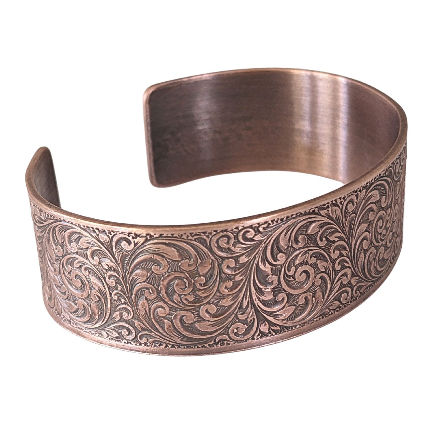 copper cuff bracelet with a detailed design of flourishes in a repeated spiral pattern