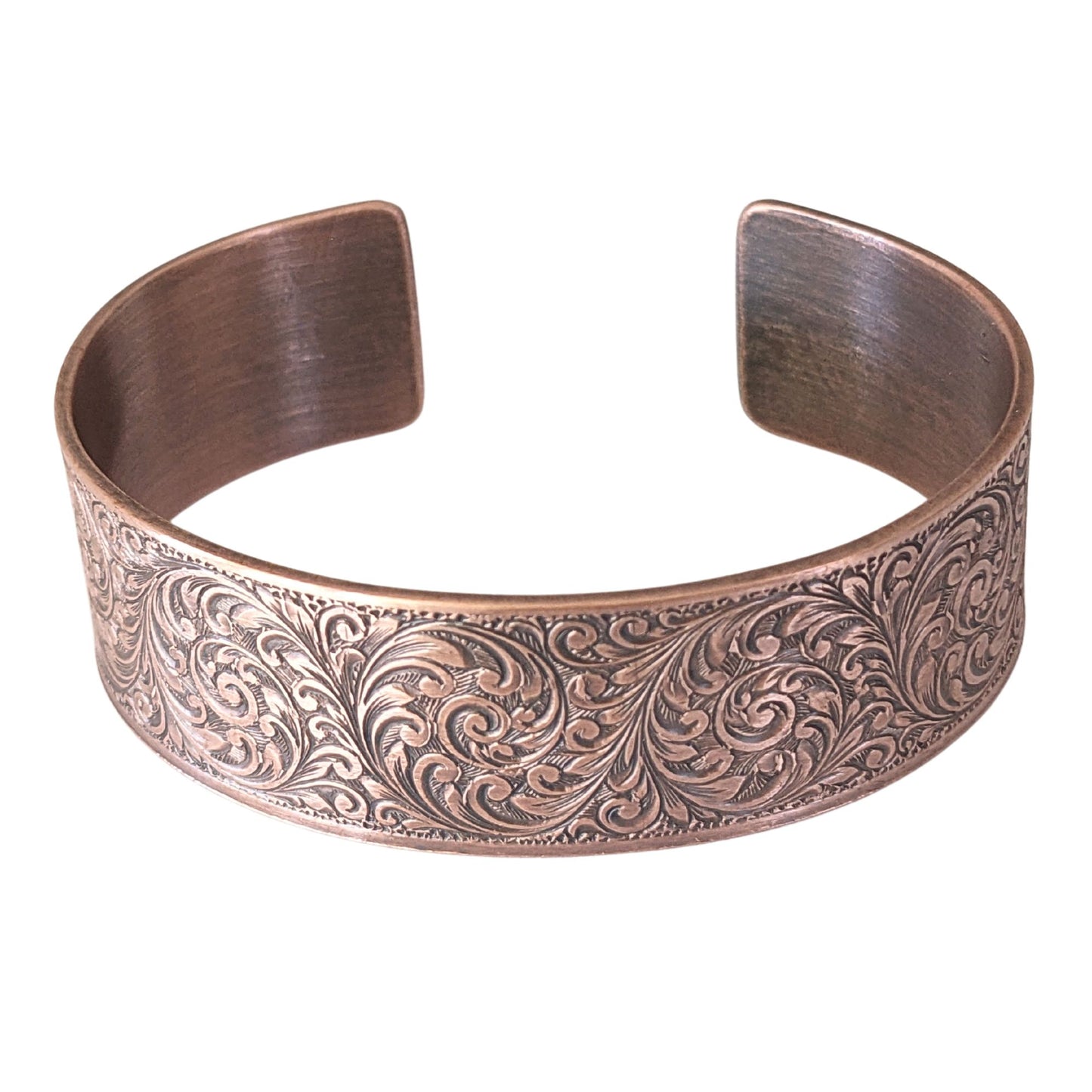 copper cuff bracelet with a detailed design of flourishes in a repeated spiral pattern