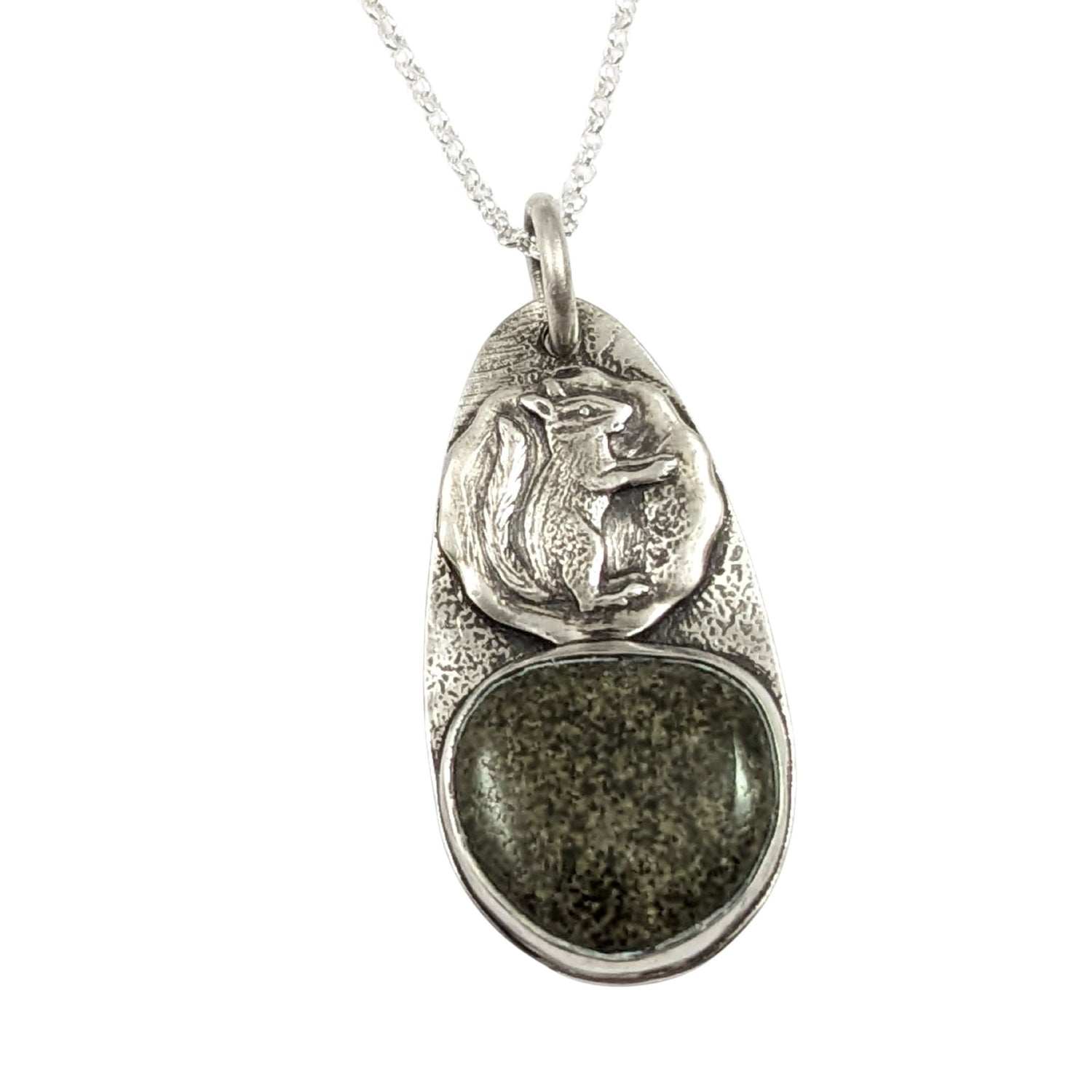 Oval sterling silver pendant. The top half has a circle with a raised image of a squirrel, the bottom half is a speckled green and tan stone.