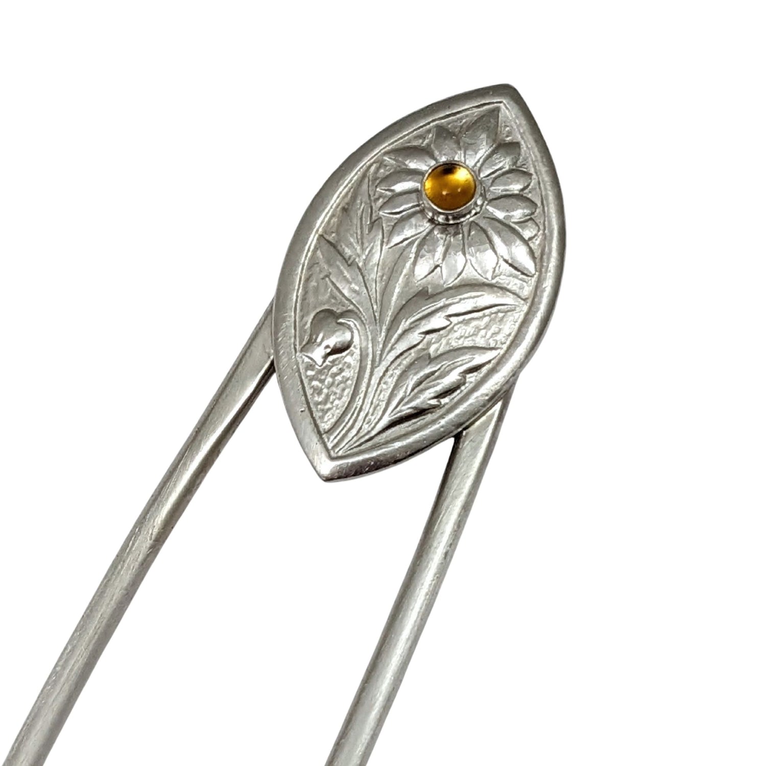 Sterling silver hair fork. The design at the top is a framed pointed oval with a sunflower plant scene. There is a yellow citrine gemstone in the middle of the sunflower.