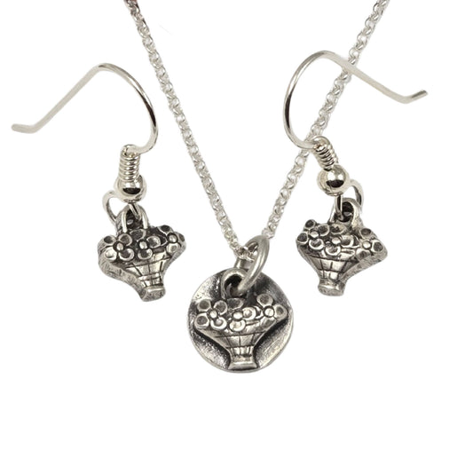 Earrings and necklace, each with a tiny hand basket full of flowers. All are silver.