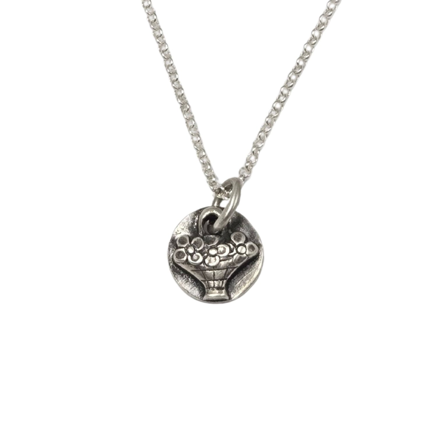 Necklace of a tiny hand basket full of flowers in silver.