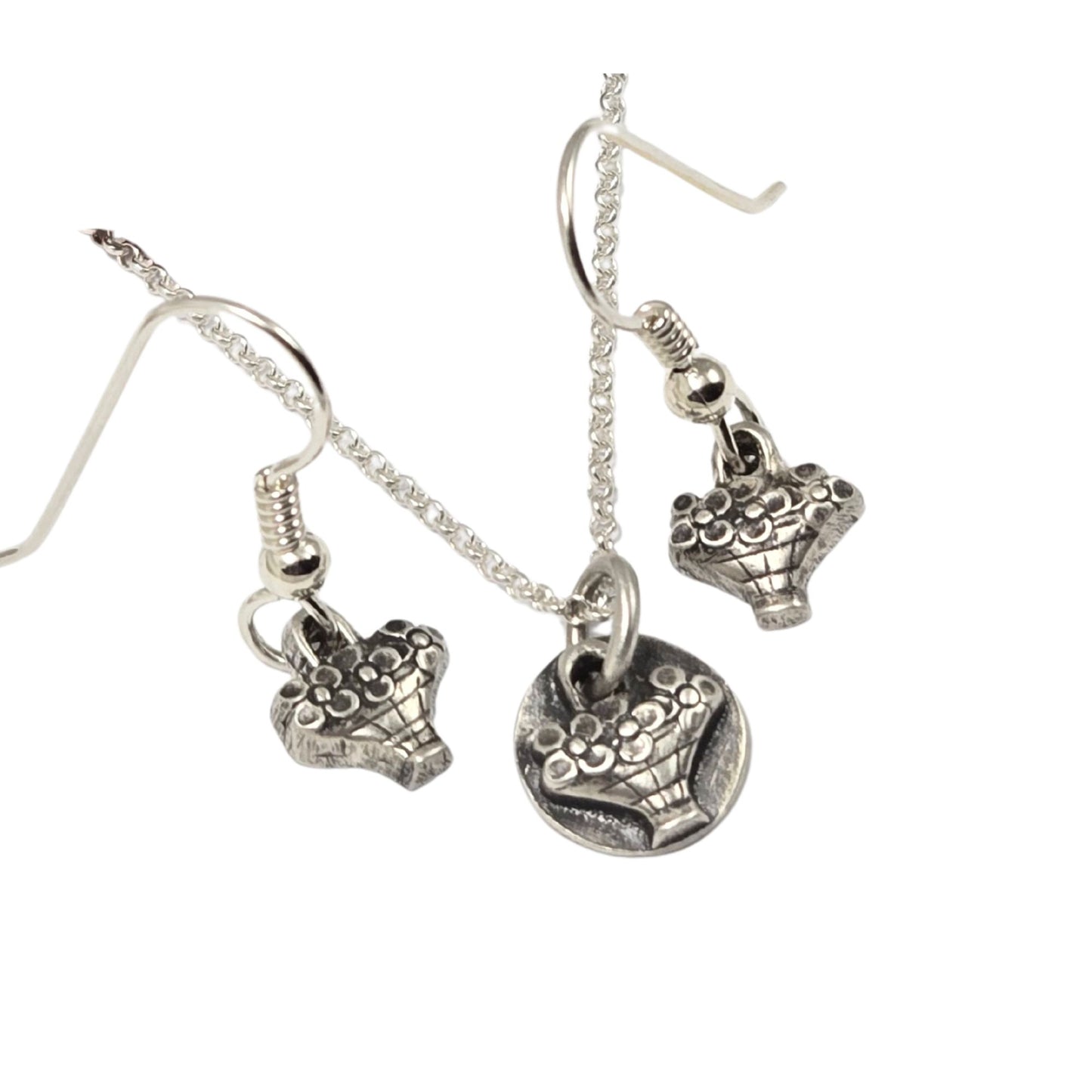 Earrings and necklace, each with a tiny hand basket full of flowers. All are silver.