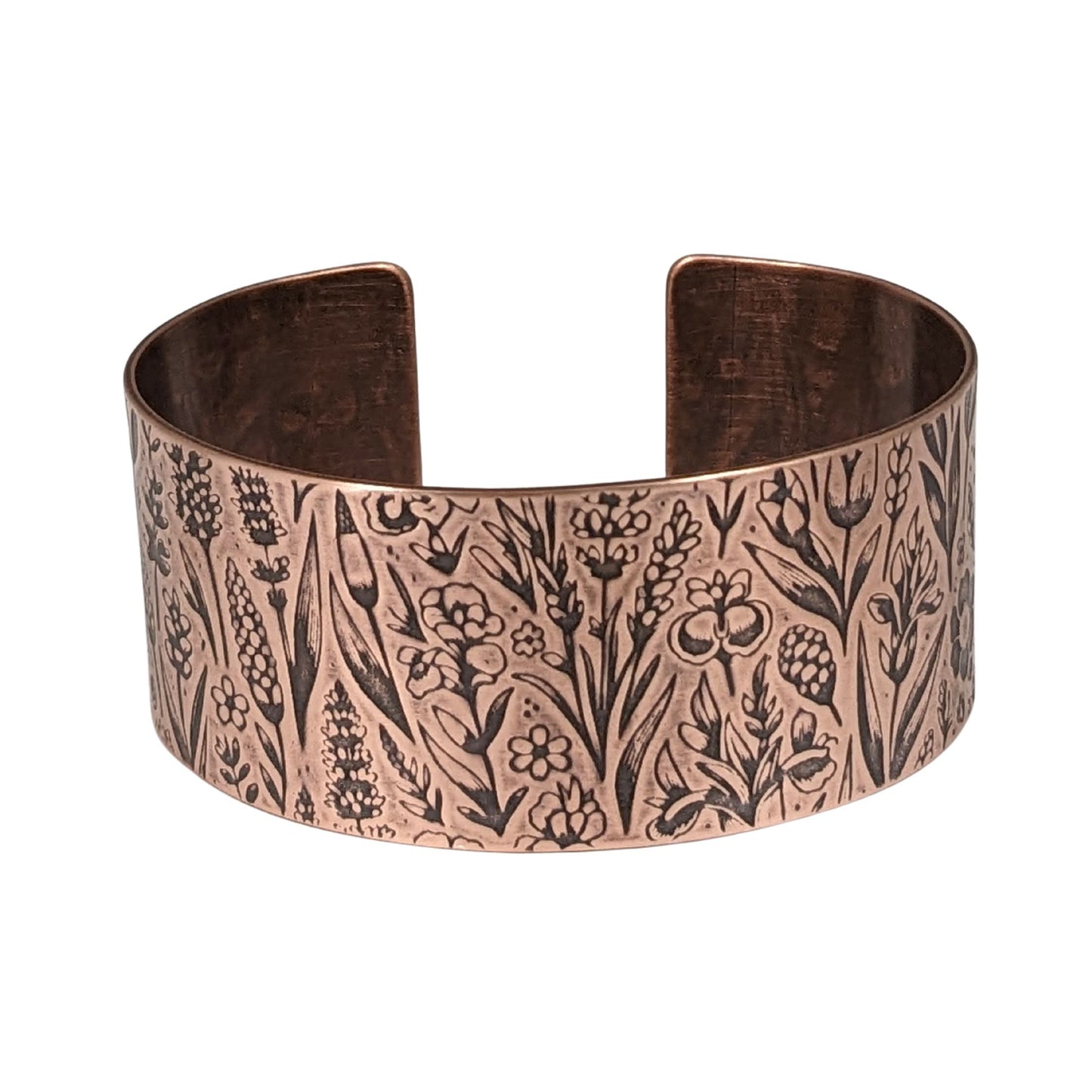 Inch wide copper cuff bracelet covered in impressed design of assorted wildflowers.