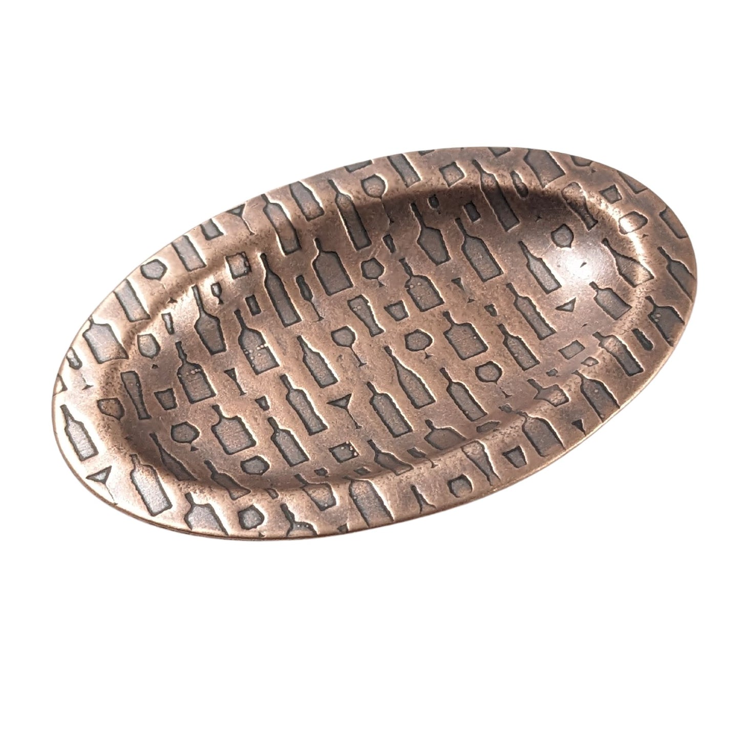 An oval copper ring dish with a raised edge. The dish has an impressed designs of wine and cocktail glasses plus wine and liquor bottles.