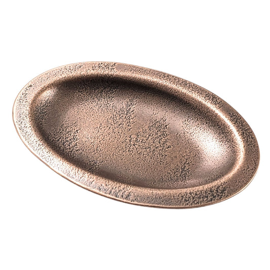 An oval copper ring dish with a raised edge. The dish has an impressed design of evergreen fir trees in the snow.