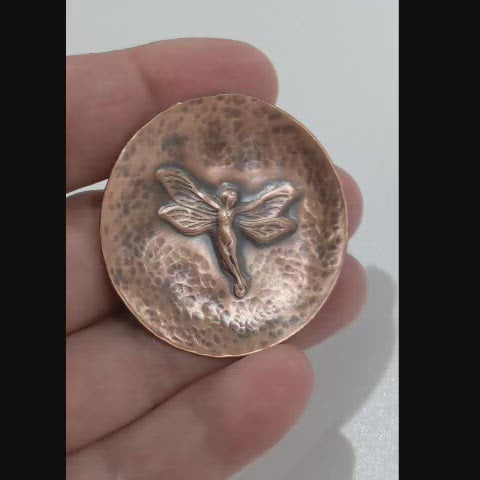 Small copper copper dish for rings, jewelry, trinkets. In middle there is a raised image of a fairy in flight. The background is dappled hammer texture, the sides are raised to form a shallow bowl.