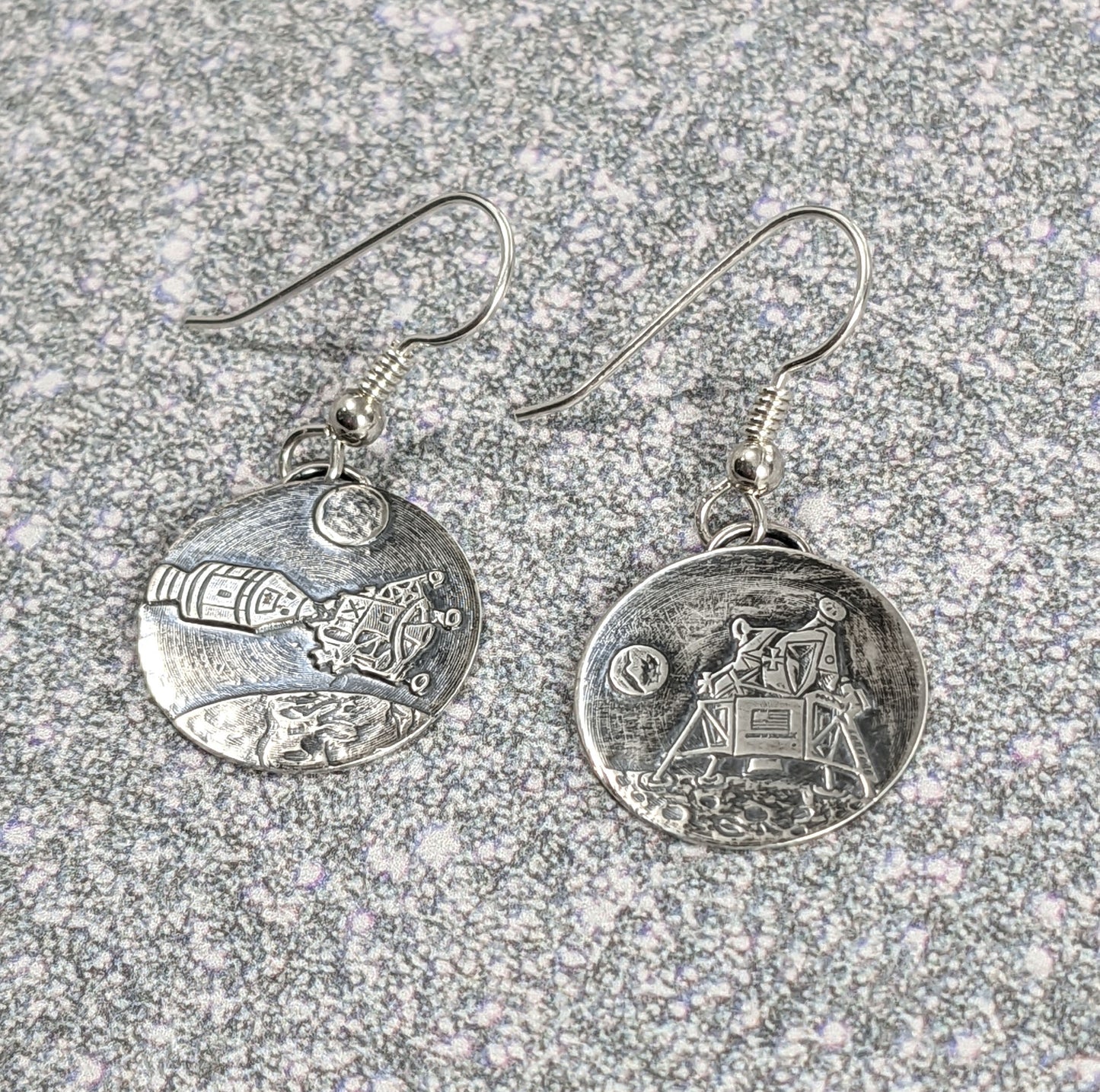 Handmade Sterling silver earrings depicting the Apollo 11 moon landing of the Eagle lunar module. One earring shows Eagle on the moon, the other shows eagle docking with the other module