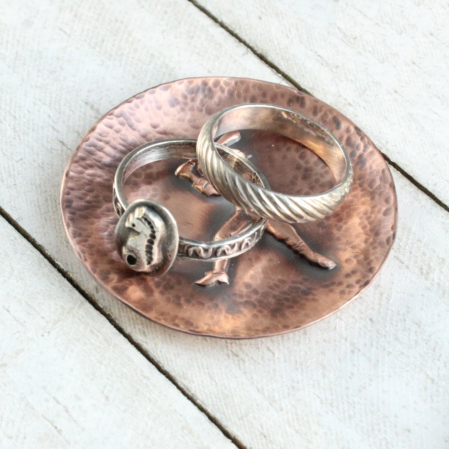 Small copper ring or trinket dish with raised impression of an old time baceball player at bat. The dish edges have a hsammered dappled texture and the edges are slightly curved up to form a shallow bowl.