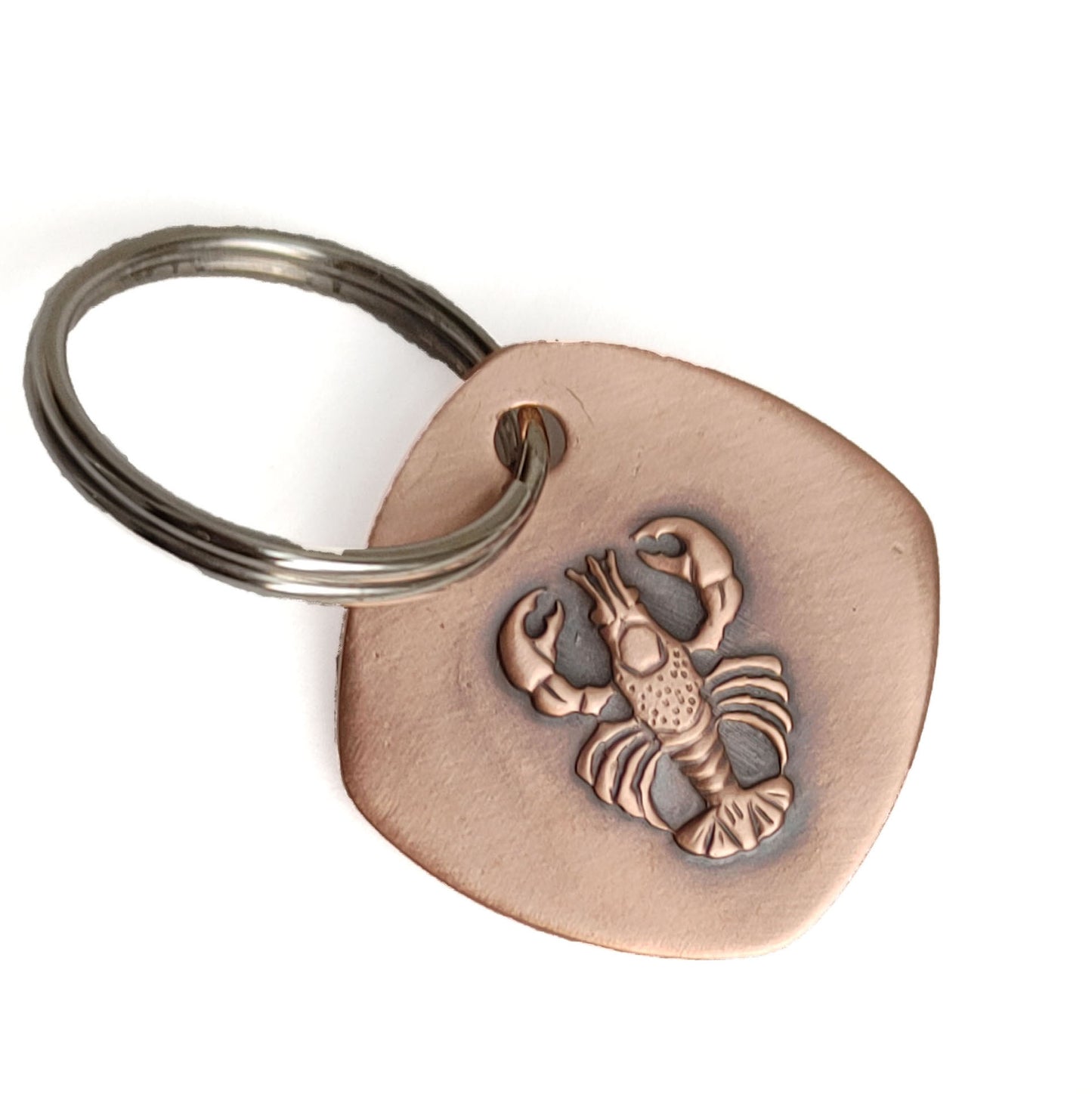 Copper keychain with a detailed raised impression of a lobster. The claws, legs, and tail are all clearly defined. The keychain is a rounded square shape.