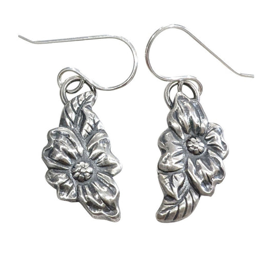 Stering silver dogwood flower earrings. The Design is asymmetric, the left earring has a leaf above the flower and the right earring has a leaf below the flower.