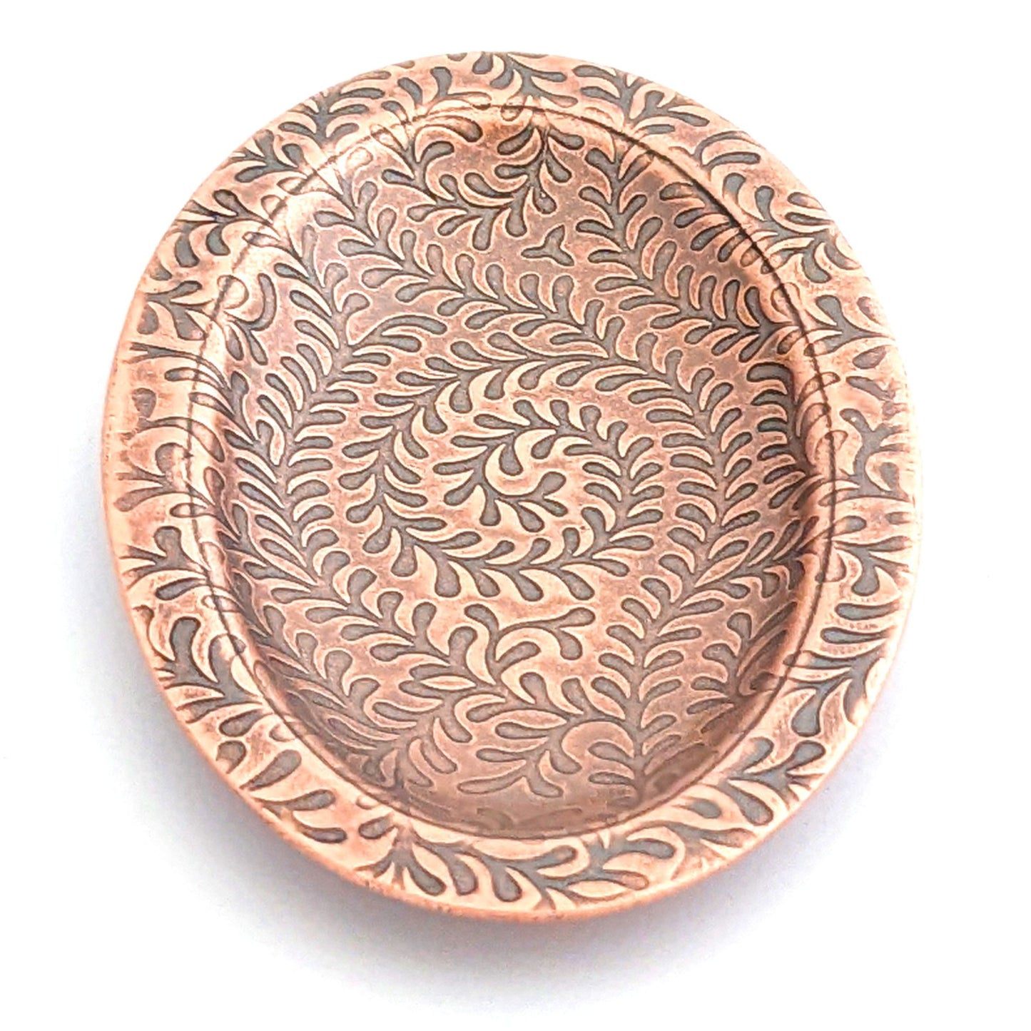 Copper oval ring dish with abstract fiddlehead fern pattern.  Dish is 2 inches by three inches with a raised lip.