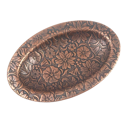 Oval copper ring dish with raised edge. Design of a variety of garden flowers, leaves, and berries covers the entire surface.