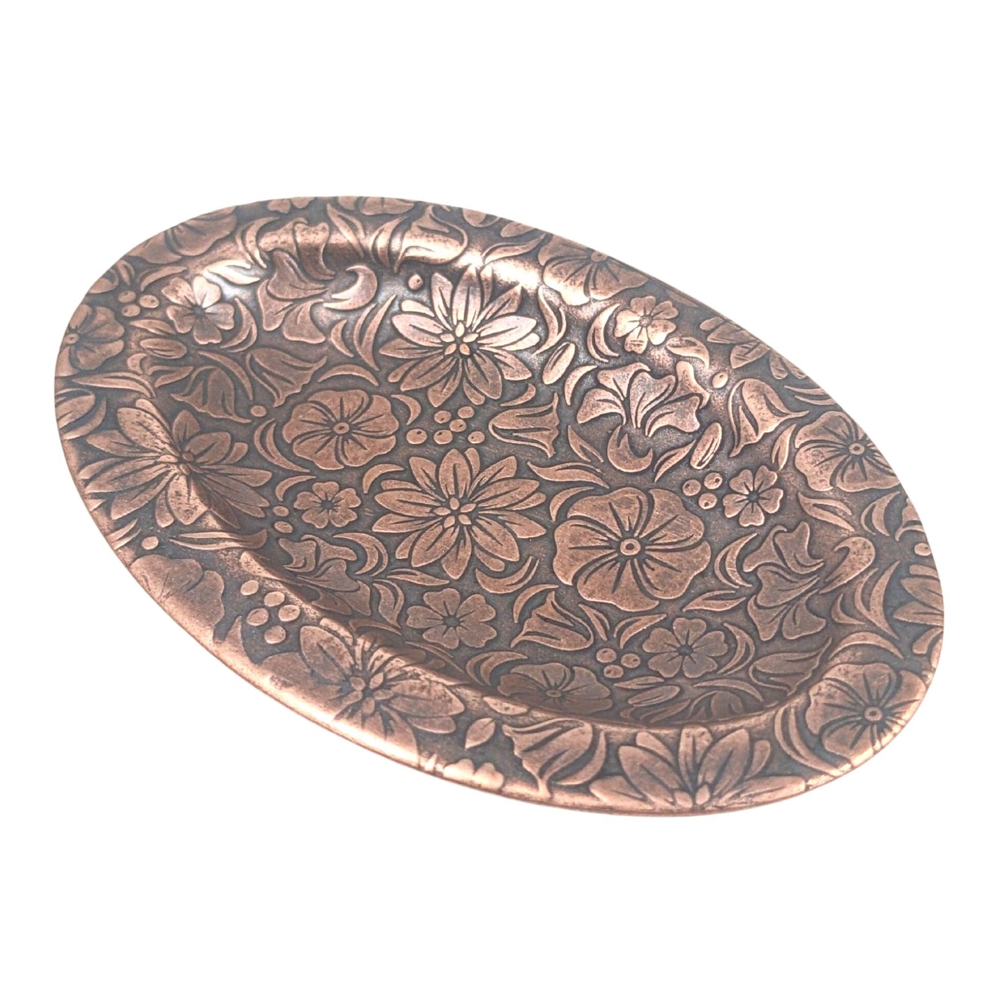 Oval copper ring dish with raised edge. Design of a variety of garden flowers, leaves, and berries covers the entire surface.