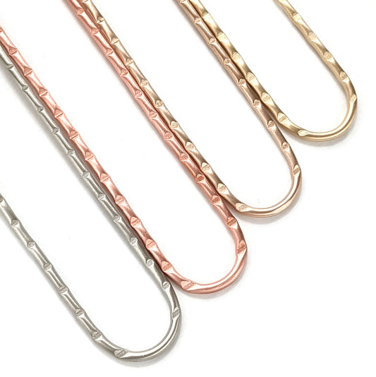 Metal hair forks shown in the four options - nickel, copper, bronze, and brass. This picture shows the detailed deep line grooves in the top portion of each hair stick.