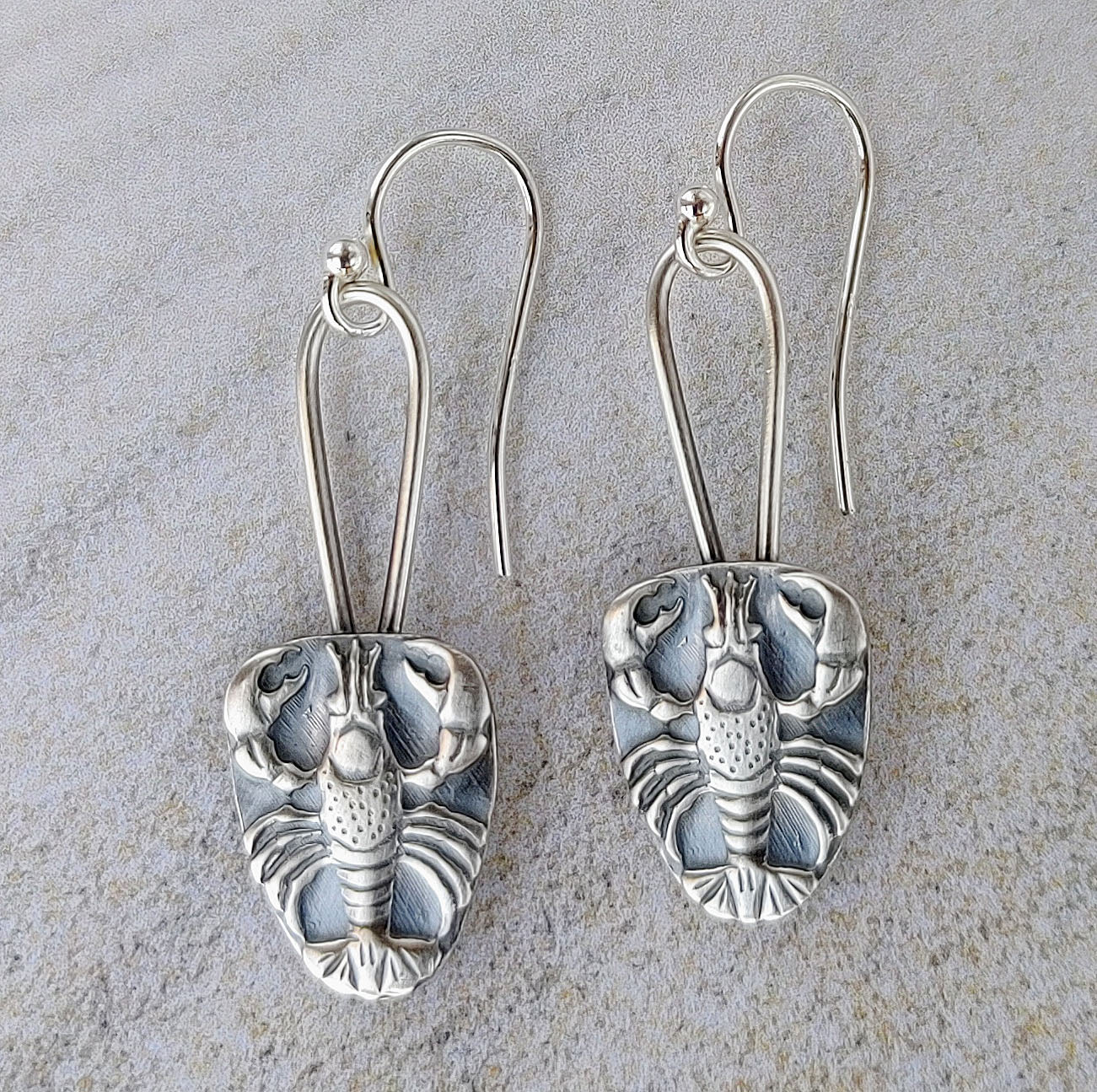Sterling silver earrings .Raised impression of a lobster on a long oval wire.