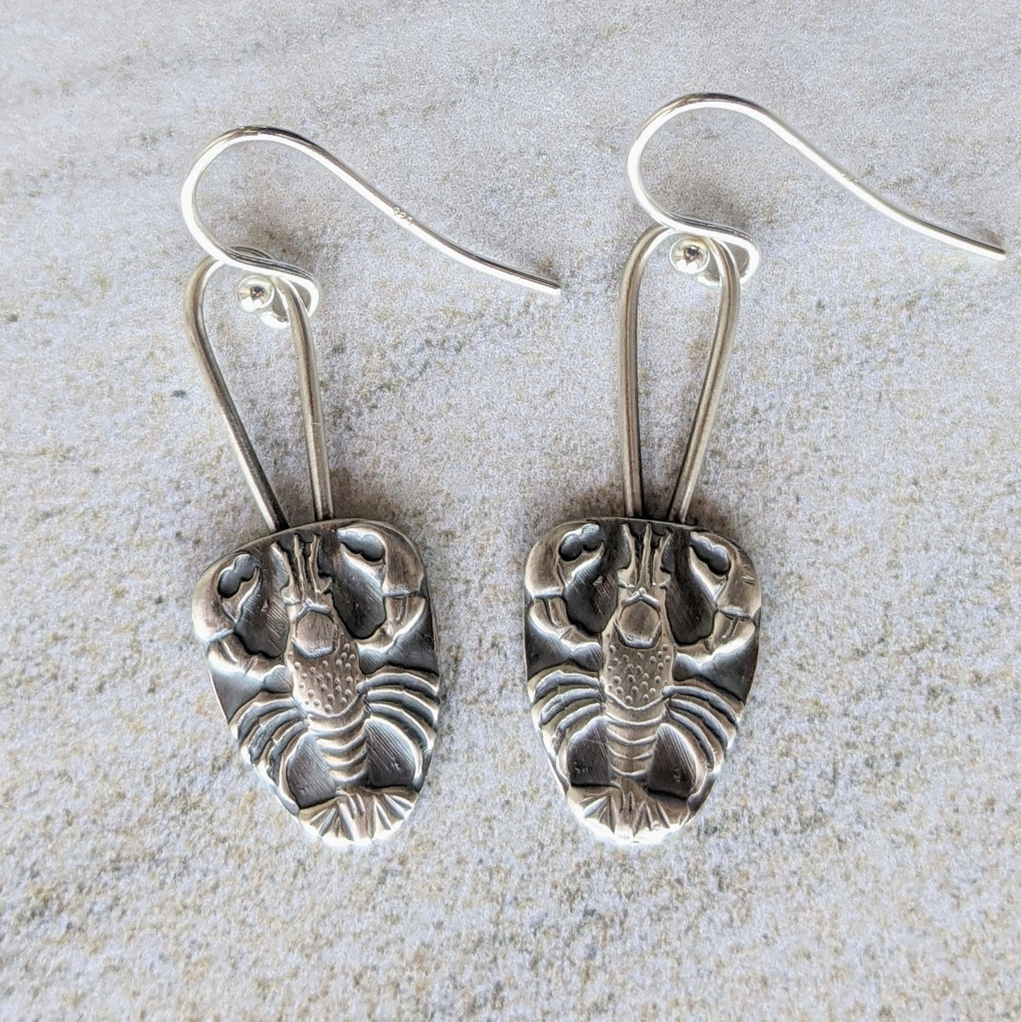 Sterling silver earrings .Raised impression of a lobster on a long oval wire.