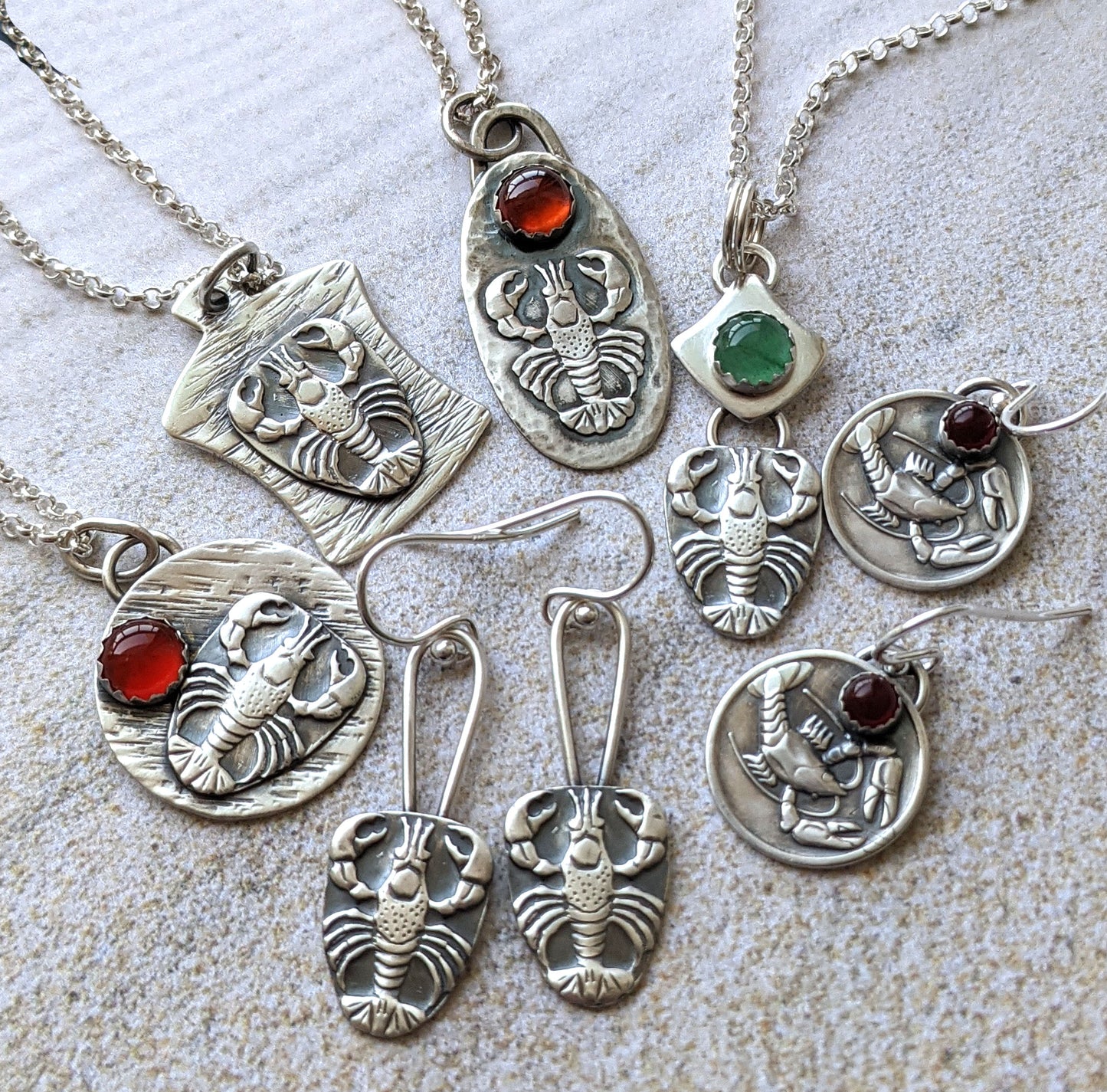 Group of lebster impression jewelry from Hennessey Jewelry. Picture shows four pendants and two pari of earrings.