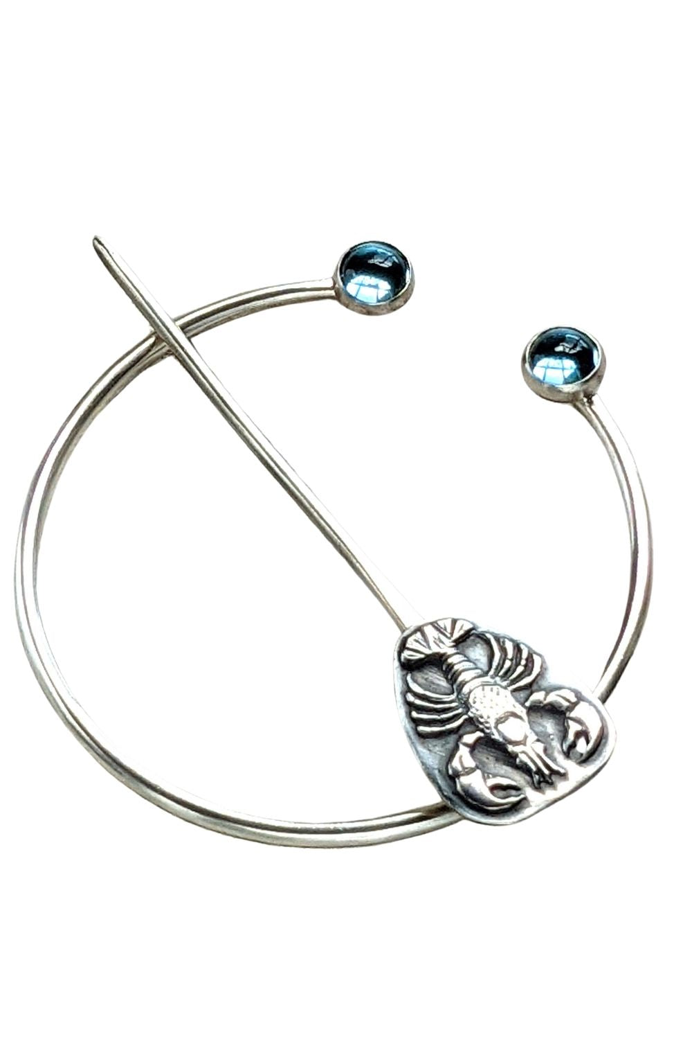 Sterling silver penannular brooch. The tip of the stem is decorated with a detailed dimensional lobster, and the ends of the loop have bright swiss blue topaz gemstone cabochons.